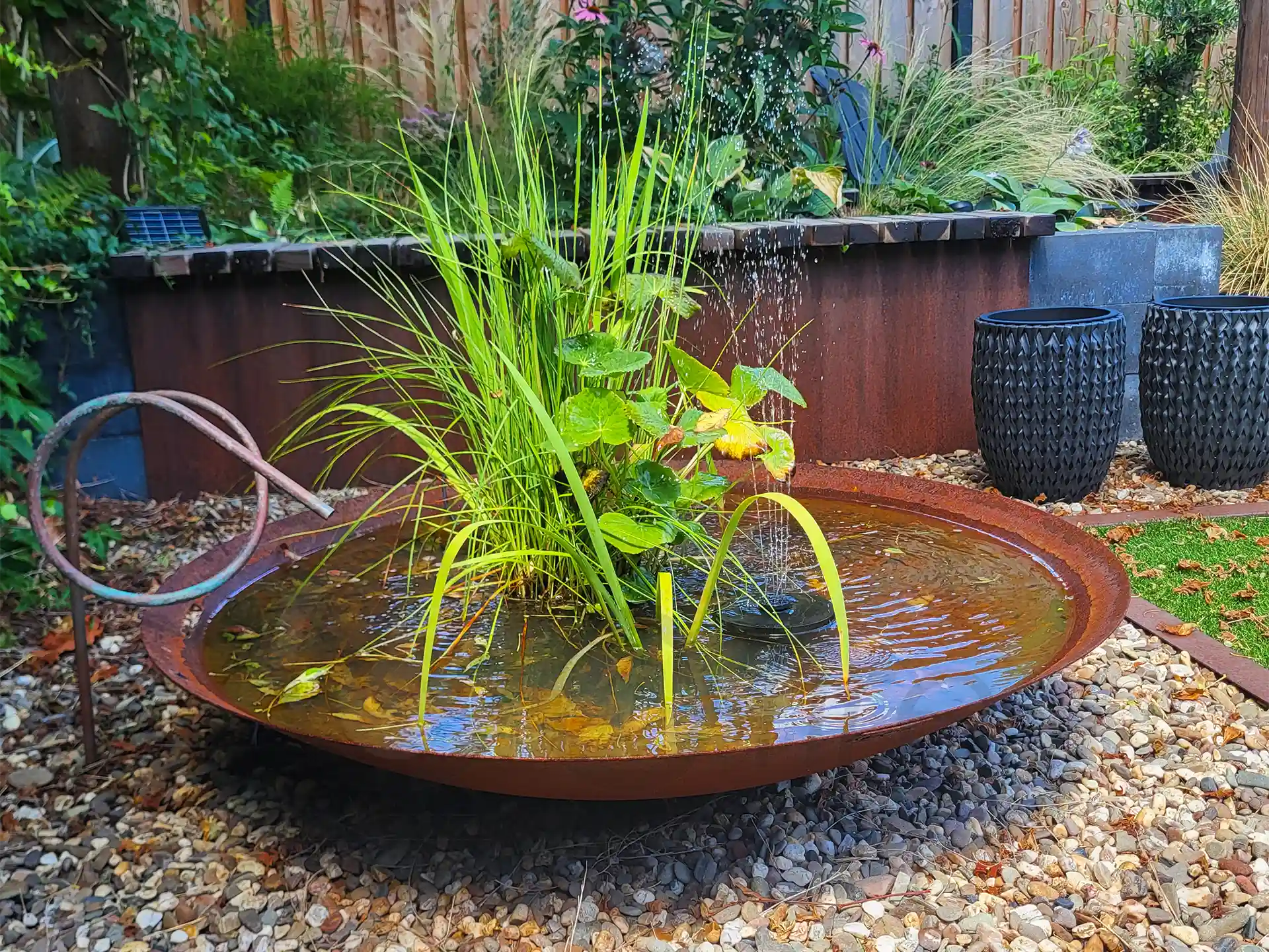 GoFire Soho waterschaal met fontein en siergrassen, omgeven door grind en tuindecoratie voor een natuurlijke en moderne uitstraling.