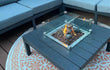 Brandende Gofire keramische stammetjes medium in een moderne loungetafelhaard op een terras met tuinmeubels.