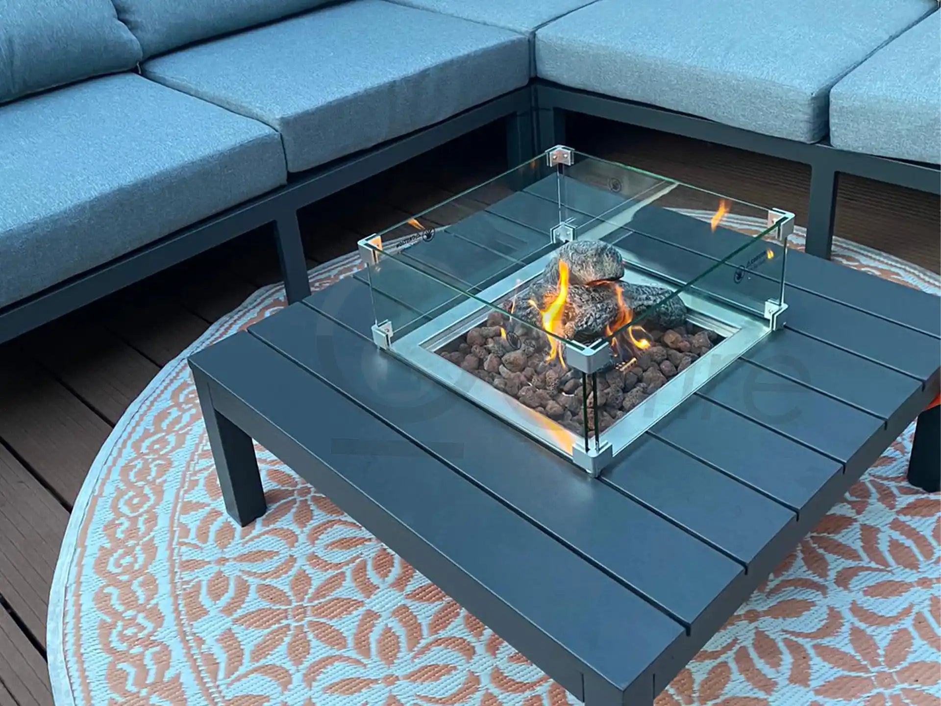 Brandende Gofire keramische stammetjes medium in een moderne loungetafelhaard op een terras met tuinmeubels.