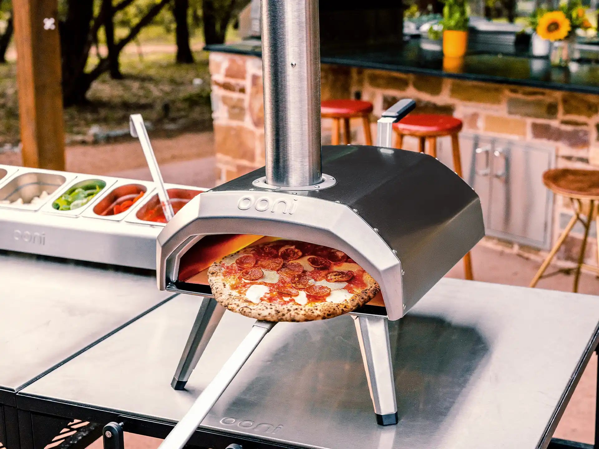 Ooni Karu 12 pizza oven in gebruik op tafel, hout- of houtskoolgestookte oven met pizza in de opening.