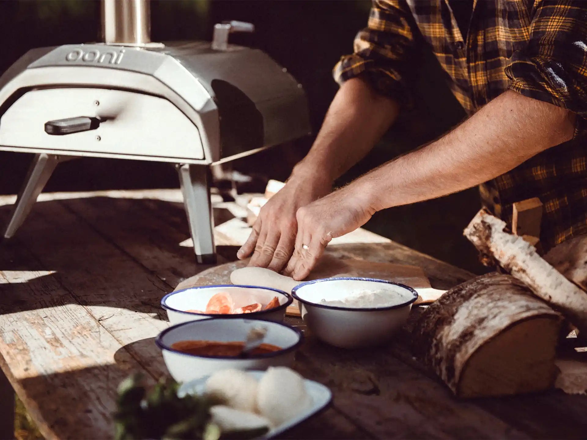 Ooni Karu 12 pizza oven in gebruik tijdens pizza bereiden, sfeervolle setting met ingrediënten op tafel.