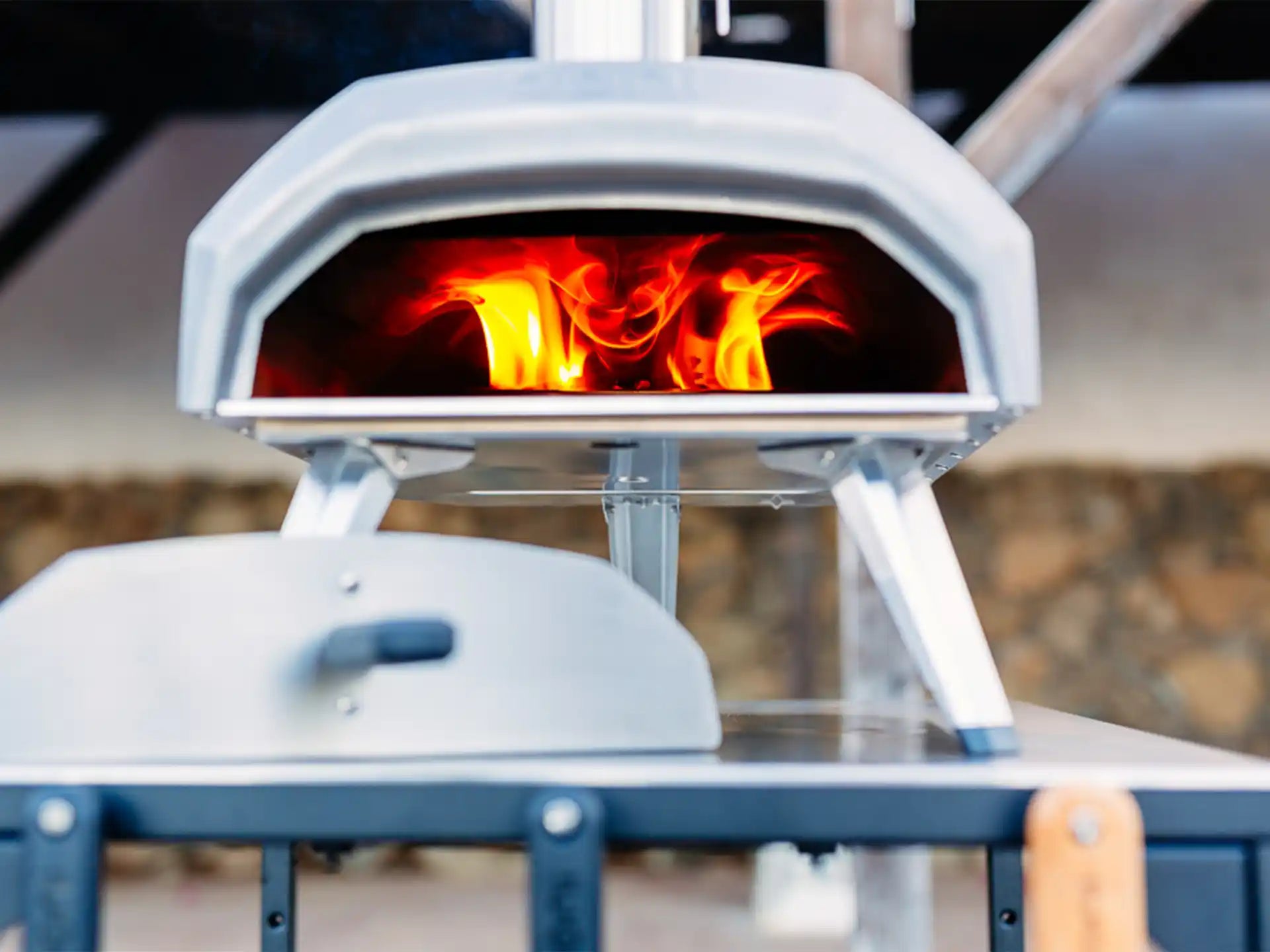 Close-up van Ooni Karu 2 hout- of houtskoolgestookte pizza oven, pizza bakt met zichtbare vlammen.