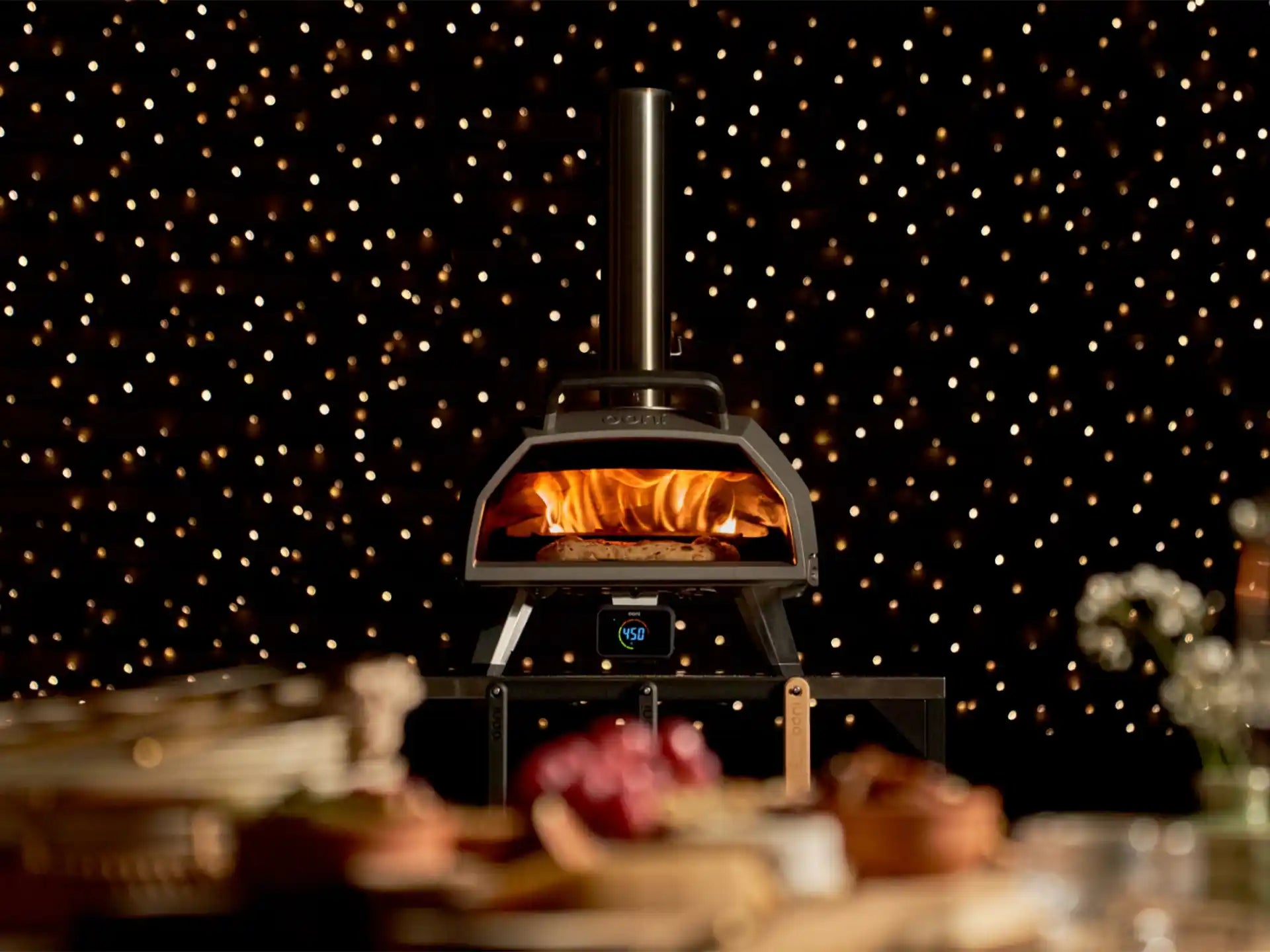 Ooni Karu 2 Pro hout- of houtskoolgestookte pizza oven, close-up met pizza in de oven en sfeervolle achtergrond.