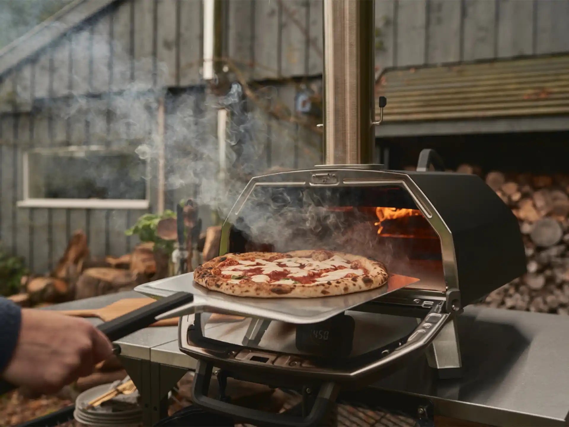 Ooni Karu 2 Pro pizza oven hout of houtskool gestookt, pizza bakt in de oven met zichtbare vlam, sfeervolle setting.