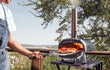 Ooni Karu 2 Pro pizza oven hout of houtskool gestookt, geplaatst buiten met pizza die bakt in de oven.
