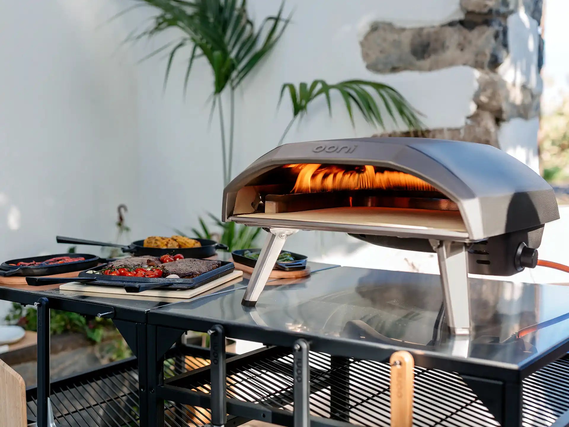 Ooni Koda 12 pizza oven op tafel buiten, pizza bakt in de gasgestookte oven, zomerse sfeer.