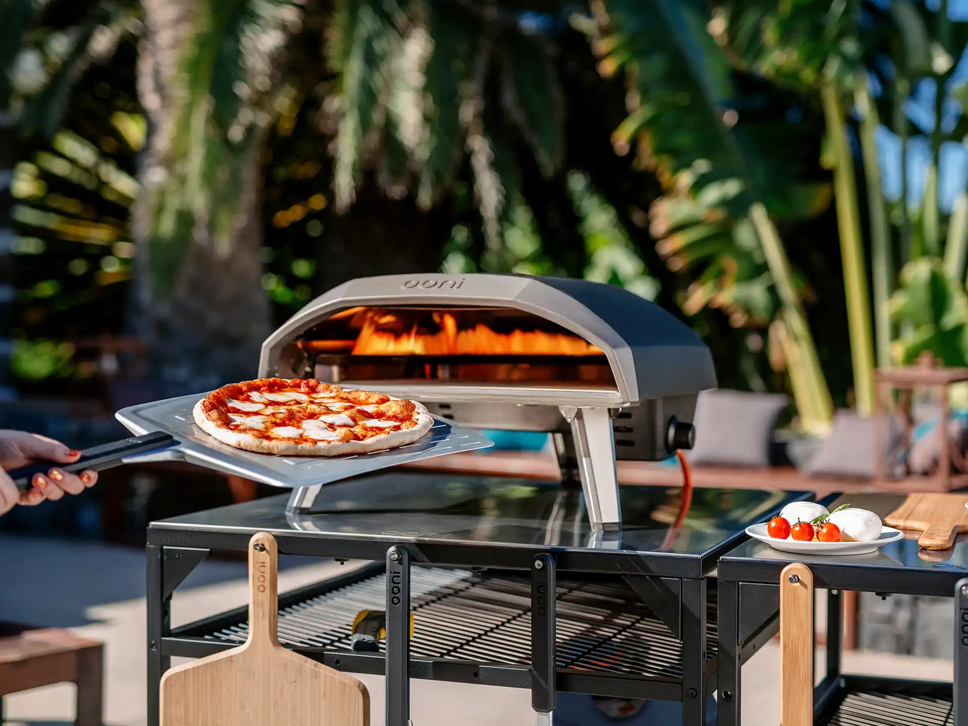 Ooni Koda 12 pizza oven buiten in een zonnige setting, pizza bakt in de gasgestookte oven op tafel.