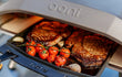 Ooni Koda 12 gas pizza oven buiten in gebruik, gevuld met groenten en vlees, close-up van de oven met gerecht.