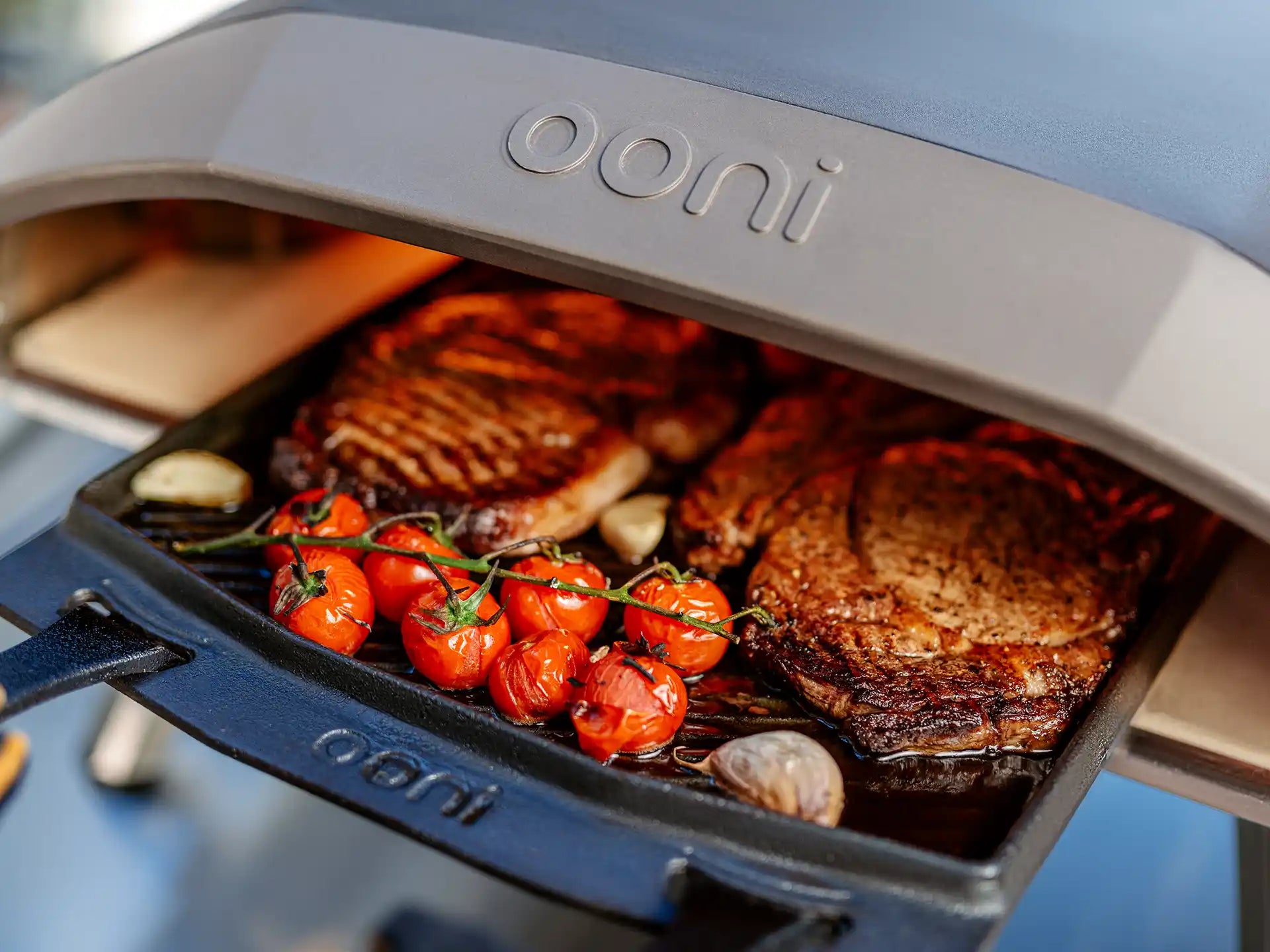 Ooni Koda 12 gas pizza oven buiten in gebruik, gevuld met groenten en vlees, close-up van de oven met gerecht.