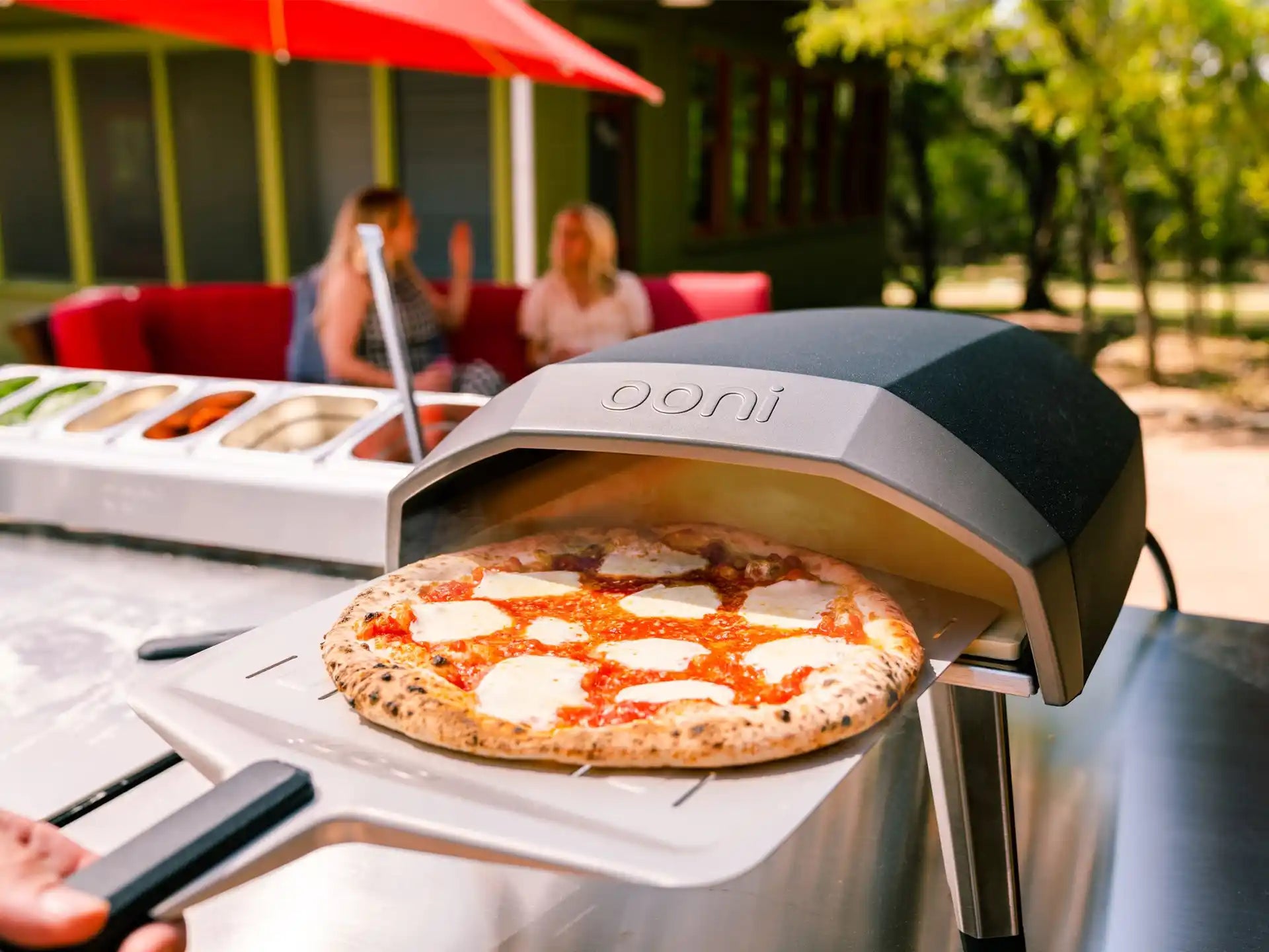 Ooni Koda 12 gas pizza oven buiten in gebruik, verse pizza op baksteen in de oven, sfeervolle setting.