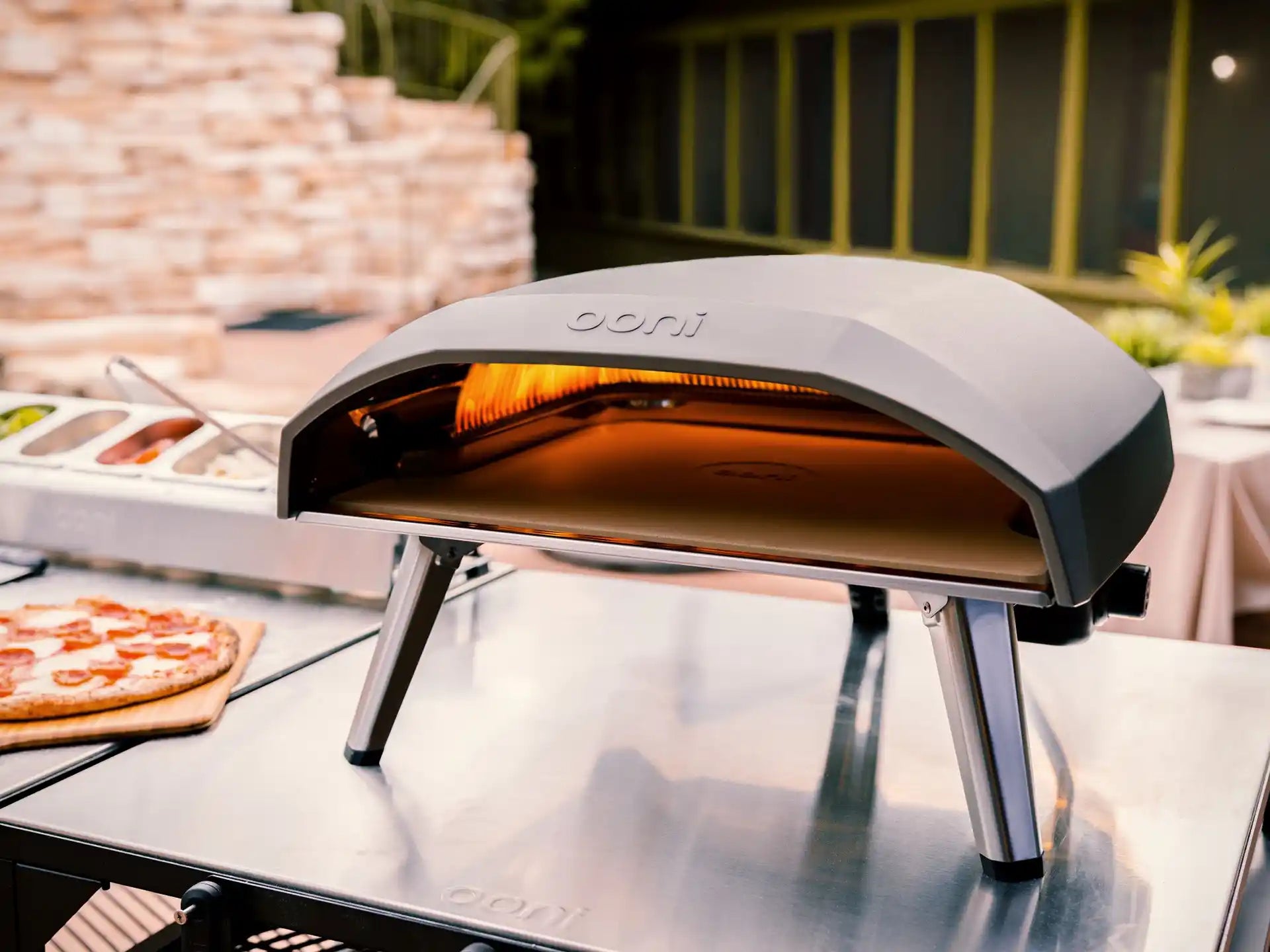 Ooni Koda 16 gasgestookte pizza oven buiten op tafel, pizza bakt in de oven tijdens gebruik.