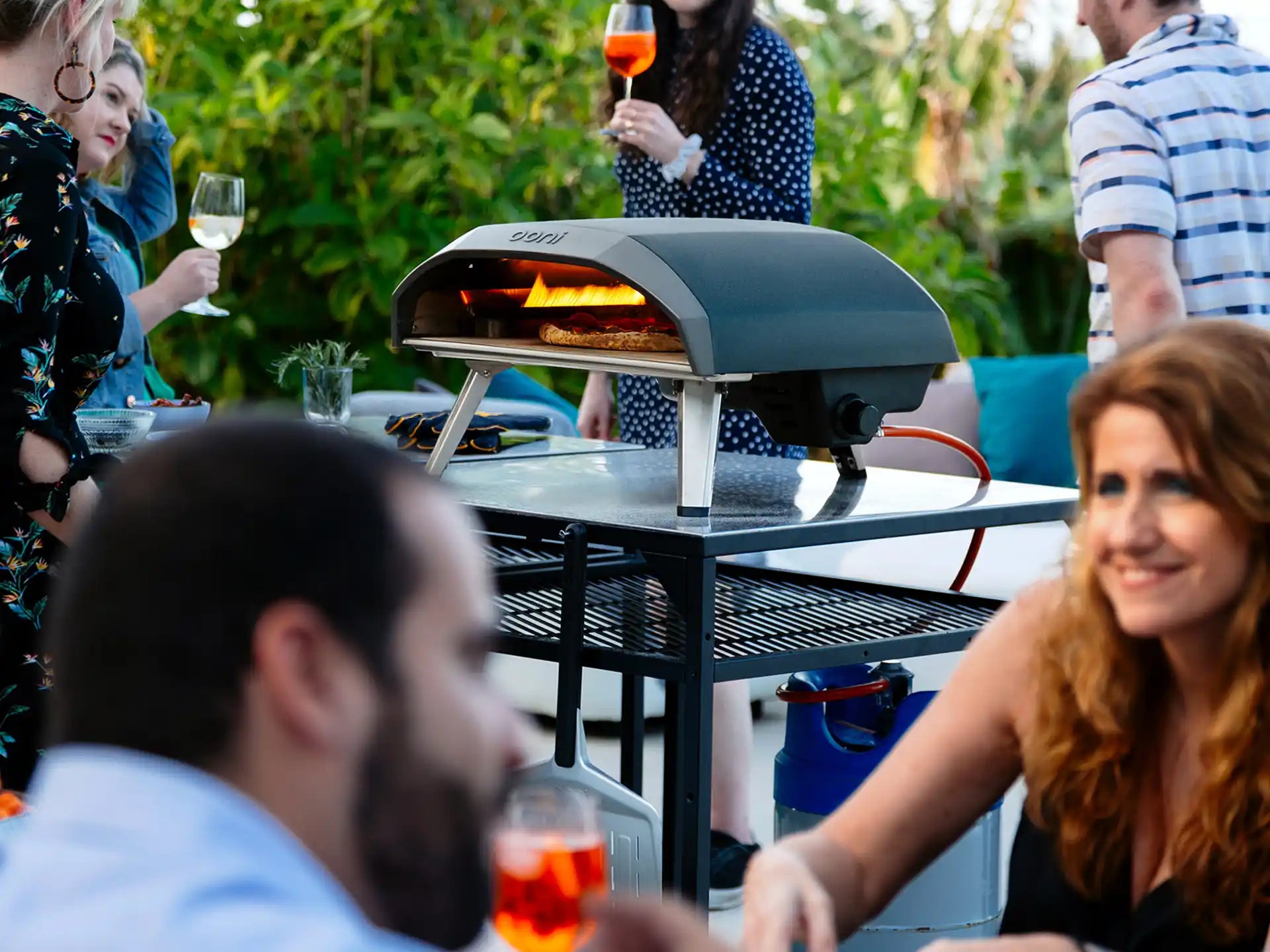 Ooni Koda 16 pizza oven op gas, in gebruik tijdens een gezellig etentje buiten met meerdere personen.