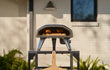 Ooni Koda 2 gasgestookte pizza oven buiten op tafel, geplaatst in de tuin tijdens gebruik.
