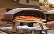 Ooni Koda 2 Max gasgestookte pizza oven in gebruik buiten, pizza bakt in de oven met zichtbare vlam.