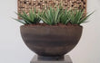 Bocca Adezz Cortenstaal Plantenbak Rond met bodem, gevuld met groene planten en geplaatst op een sokkel in een interieur.