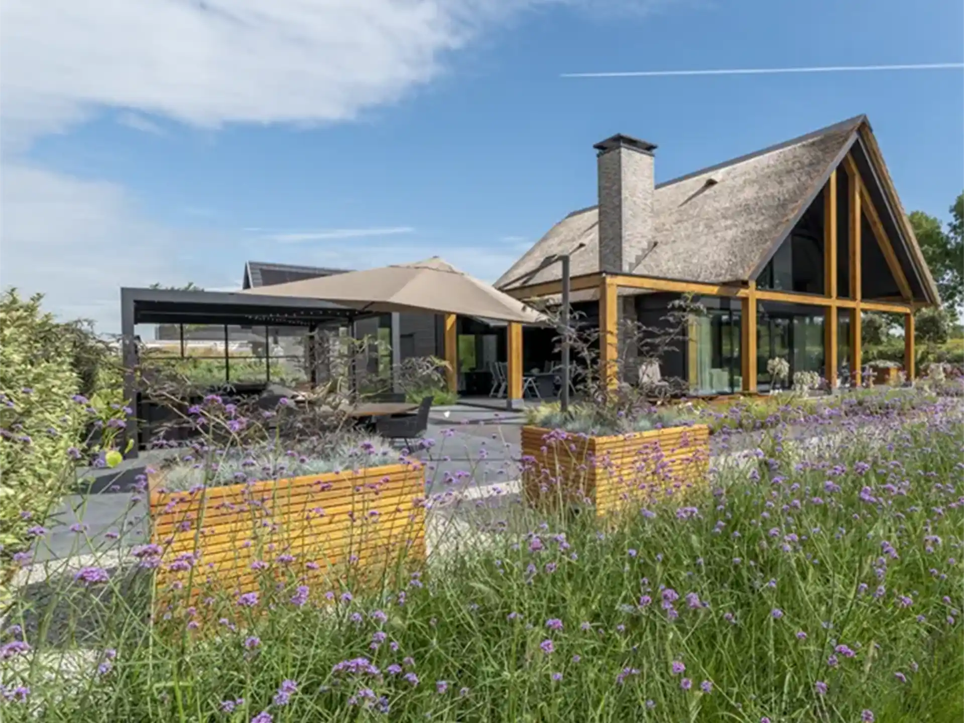 Adezz Malaga Rhombus hardhouten plantenbak, gevuld met een boom en groen op een moderne patio.