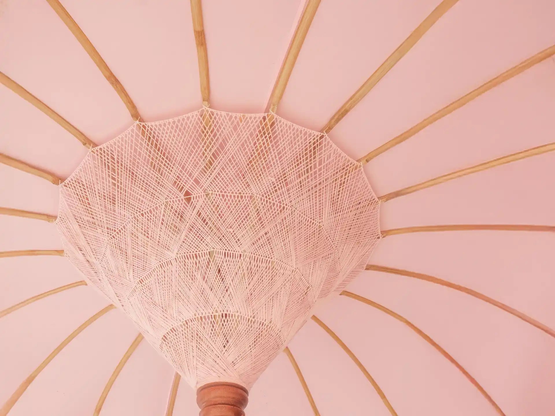 Roze Bali parasol van Todo Bien met decoratieve kwastjes en hangers, stijlvolle en tropische parasol voor buiten.