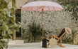 Roze Bali parasol van Todo Bien naast ligstoel bij zwembad, zorgt voor een tropische en sfeervolle tuinsetting.