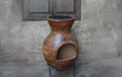 Sfeerfoto van de rode Sol-y-Yo Chimenea Mexicaanse tuinkachel Barbecue Jumbo (115 cm), brandend met open vuur en gebruikt als barbecue in een sfeervolle tuinomgeving.