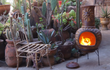 Sfeerfoto van de rode Sol-y-Yo Chimenea Mexicaanse vuurpot met zonmotief (105 cm), brandend met houtvuur in een tuin voor warmte en gezellige sfeer.