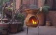 Sfeerfoto van de gele Sol-y-Yo kleine Maya BBQ terrashaard (36 x 78 cm), brandend met open vuur en gebruikt als barbecue in een sfeervolle tuinomgeving.