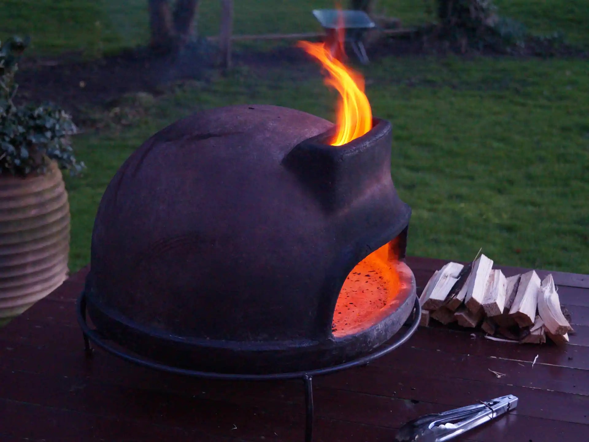 Sol-y-Yo Toscaanse houtgestookte pizza oven 52 cm, buiten geplaatst op tafel, met brandend vuur in de oven.