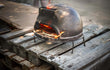 Sol-y-Yo Toscaanse houtgestookte pizza oven 52 cm, geplaatst buiten op houten vlonder, oven in gebruik met vlammen.