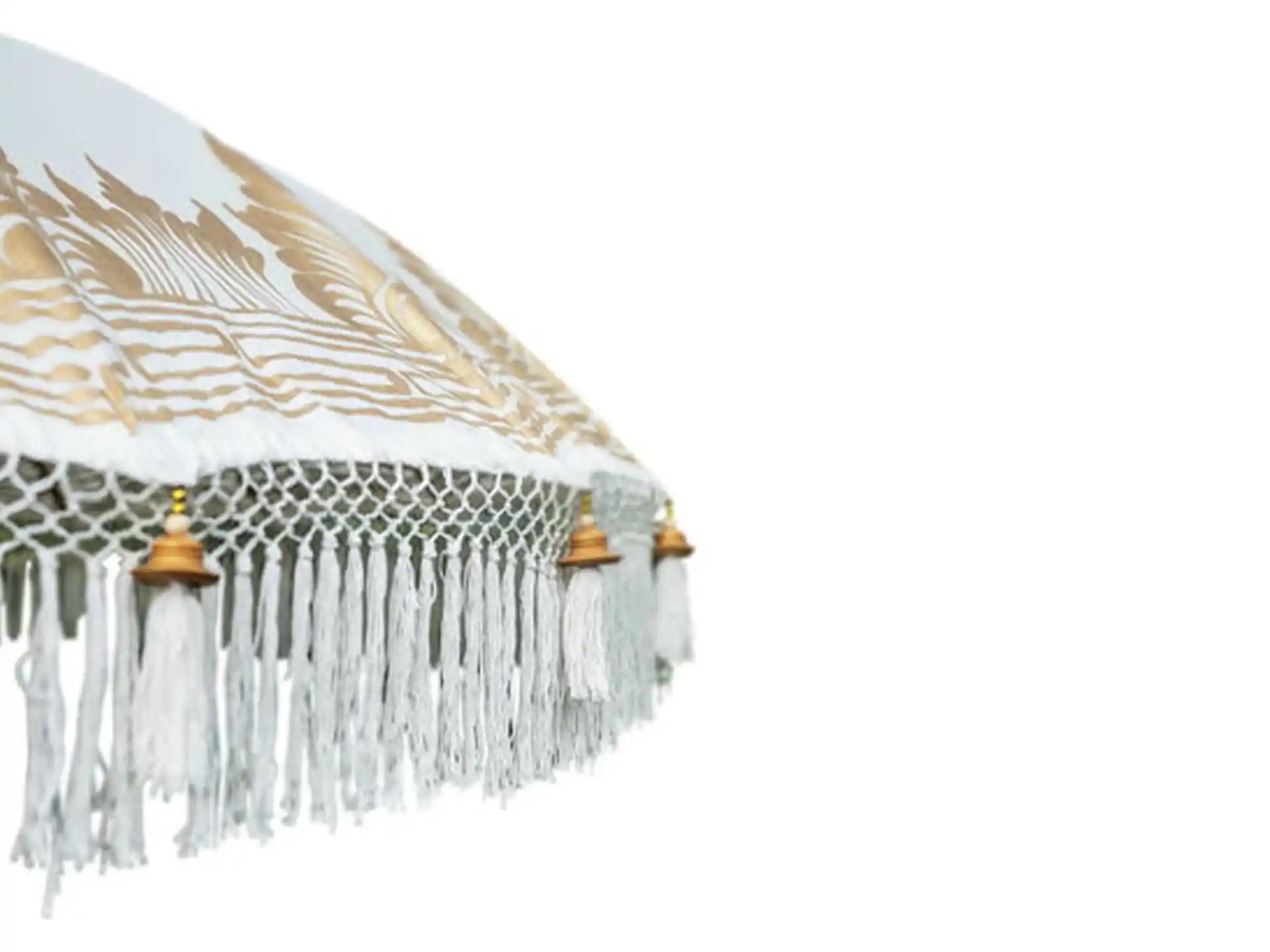 Detailopname van crème Bali parasol met gouden beschildering en sierlijke franjes langs de rand.
