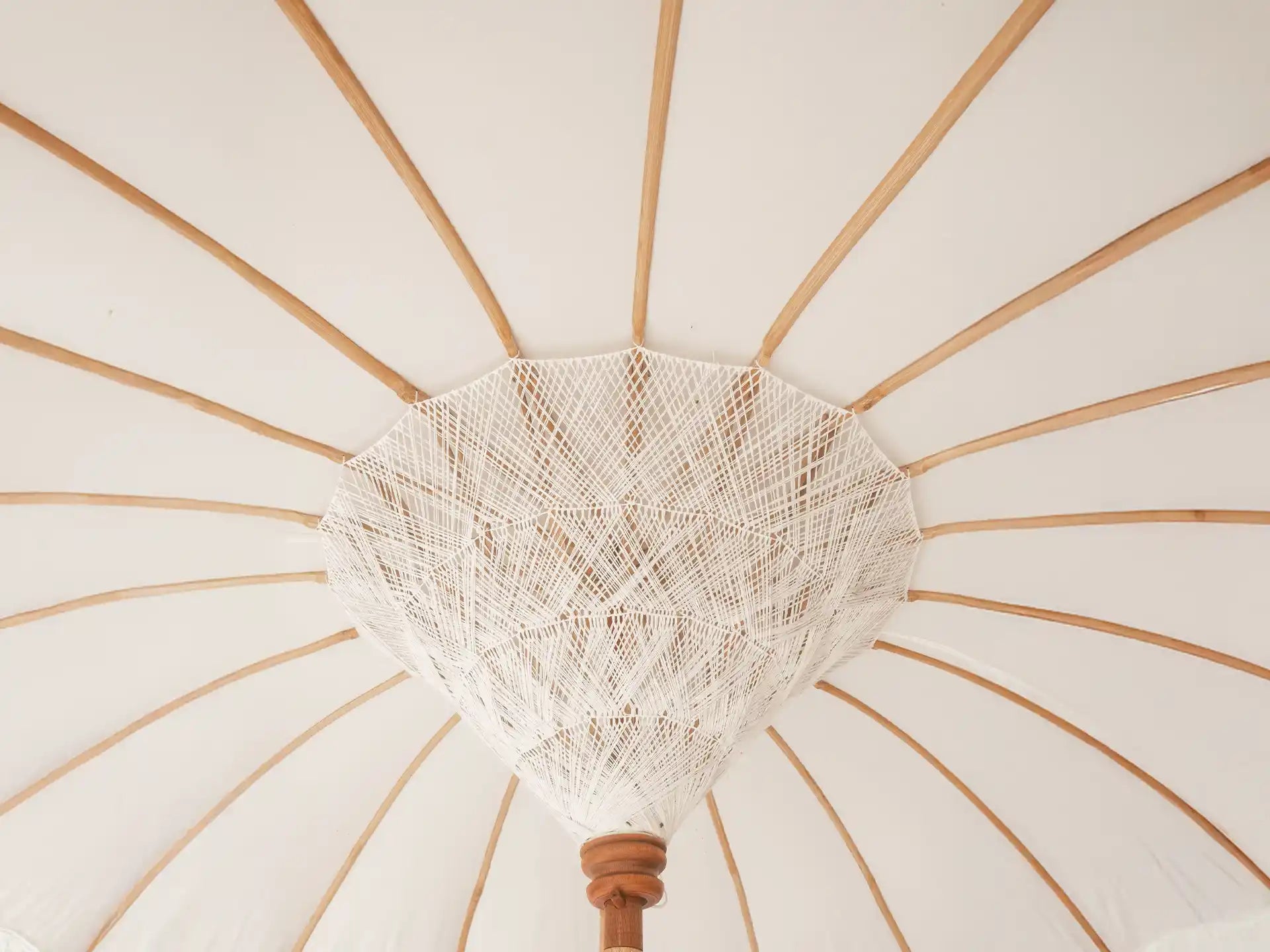 Close-up van de binnenzijde van de Todo Bien Bali parasol in crème kleur, met handgemaakte bamboe spaken en fijn geweven detail in het midden.