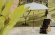 Todo Bien Bali parasol in crème kleur geplaatst in een tuin naast een houten ligstoel, ideaal voor een zomerse en sfeervolle buitenruimte.