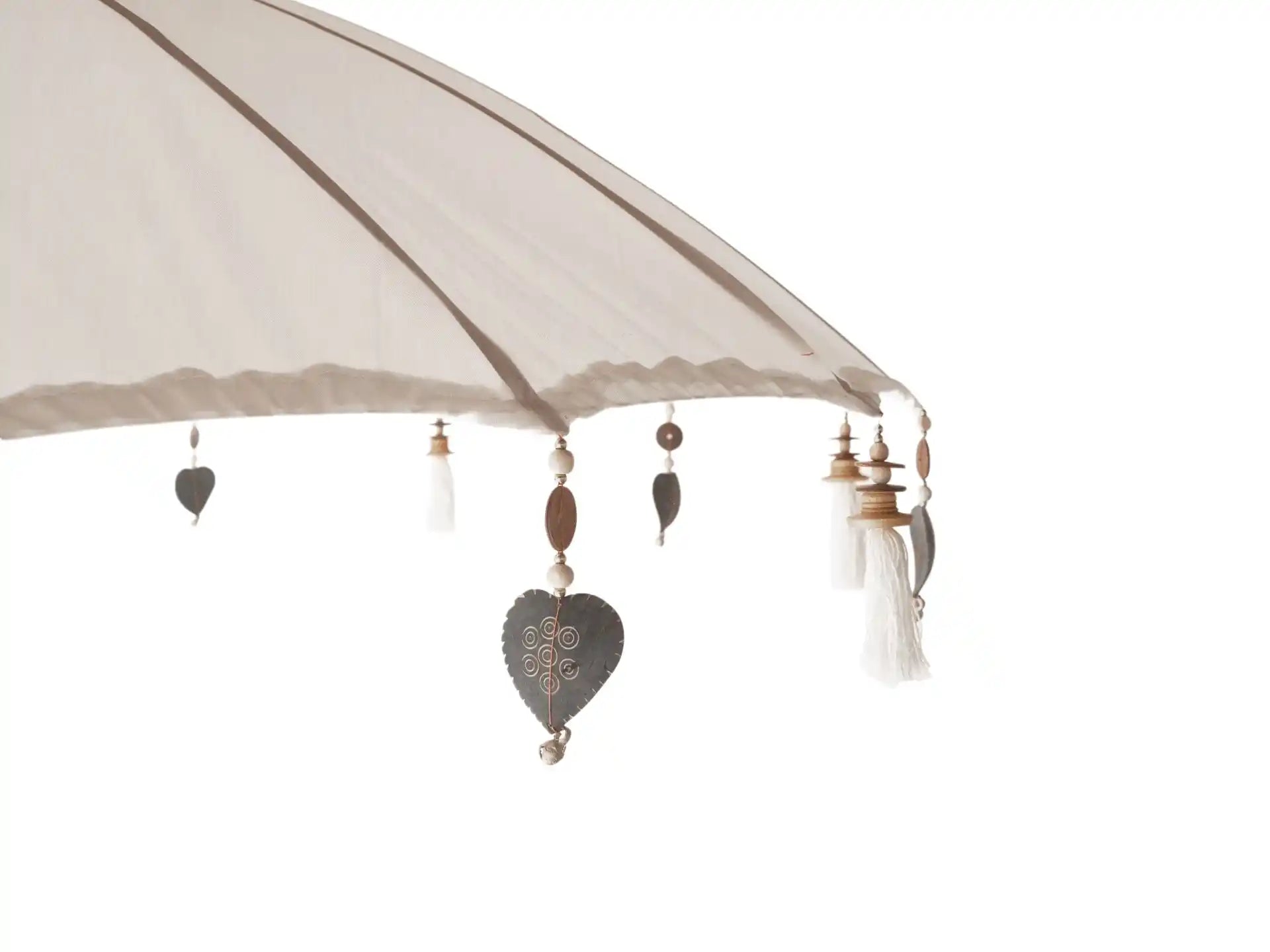 Detailfoto van de rand van de Todo Bien Bali parasol crème, voorzien van decoratieve hangers, houten kralen en witte kwastjes.