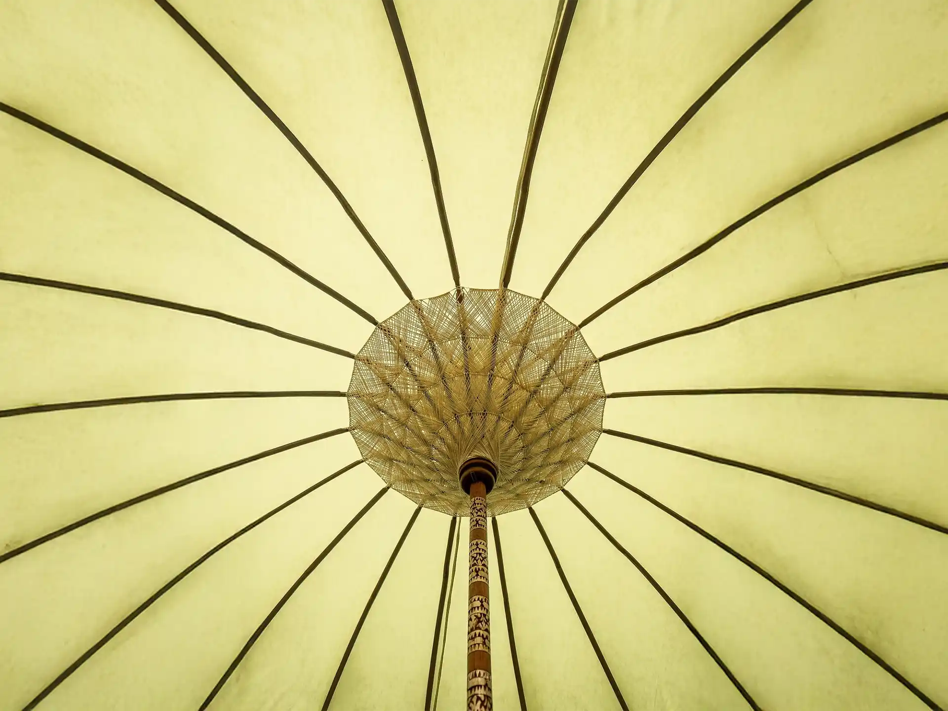 Onderzijde van de Todo Bien Bali parasol geel met decoratief geweven patroon en houten baleinen, sfeervol zomers detail.